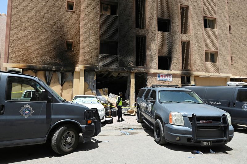 © Reuters. A Kuwaiti police officer is seen in front of a burnt building following a deadly fire, in Mangaf, southern Kuwait, June 12, 2024. REUTERS/Stringer