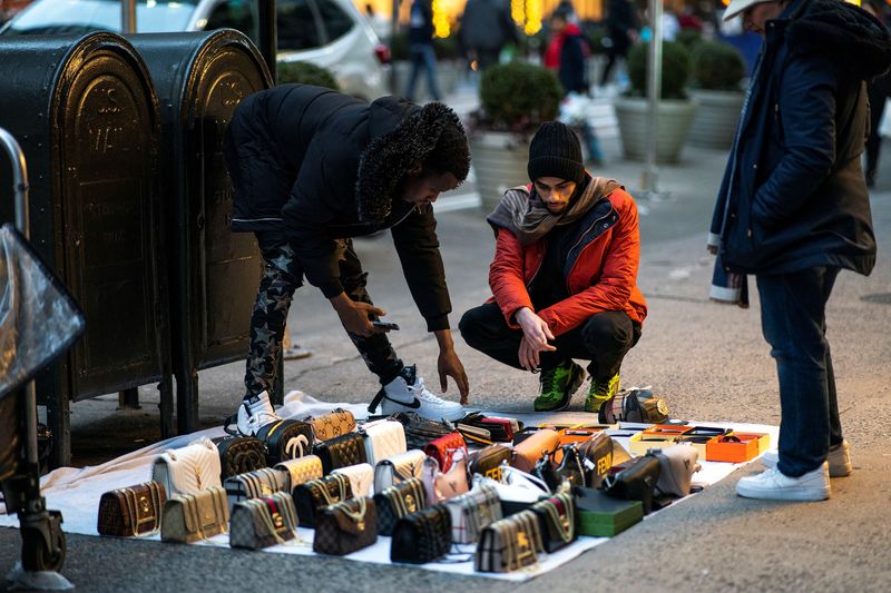 © Reuters. FILE PHOTO: A man asks for the price of some purses sold at a local street, in middle Manhattan, New York, U.S., December 25, 2023. REUTERS/Eduardo Munoz