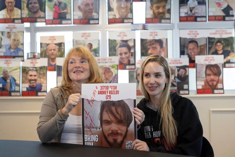 © Reuters. Evgeniia Kozlova, mother of Andrey Kozlov, and Jenifer Master, the girlfriend of Andrey Kozlov, who was taken hostage during the deadly October 7 attack by Hamas, hold a poster with Andrey's picture during an interview with Reuters after Israeli special forces rescued him from Gaza, in Tel Aviv, Israel, June 11, 2024. REUTERS/Marko Djurica