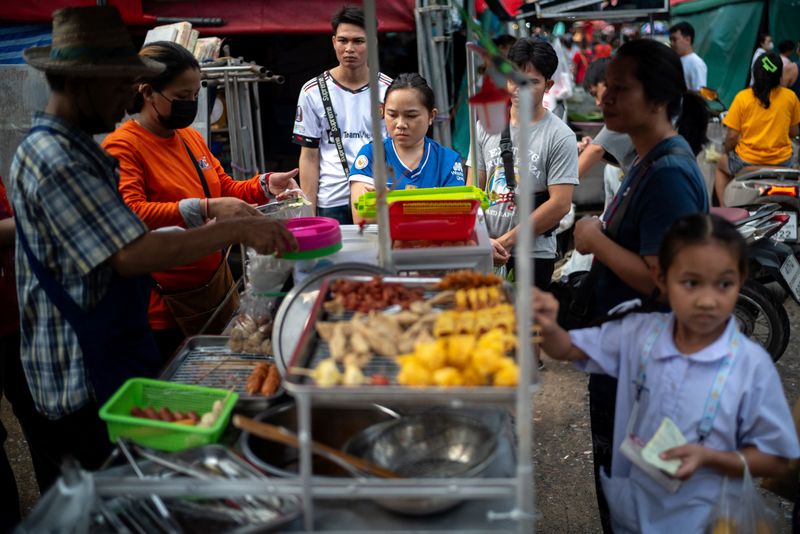 © Reuters. FILE PHOTO: People buy street food at a market as Thailand is to inject $15.2 bln into economy next year through its digital wallet policy, in Bangkok, Thailand, October 2, 2023. REUTERS/Athit Perawongmetha/File Photo