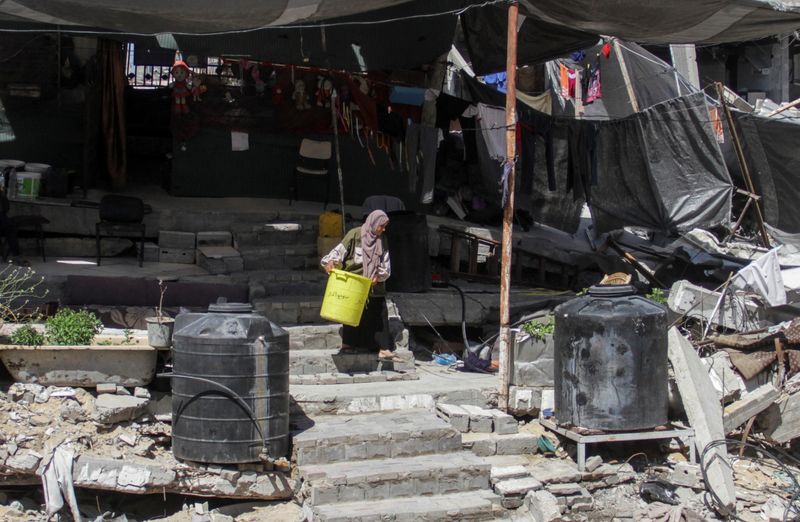 &copy; Reuters. A Palestinian woman walks among the rubble of a damaged building, which was destroyed during Israel's military offensive, amid the ongoing conflict between Israel and Hamas, in Beit Lahia in the northern Gaza Strip, June 12, 2024. REUTERS/Mahmoud Issa