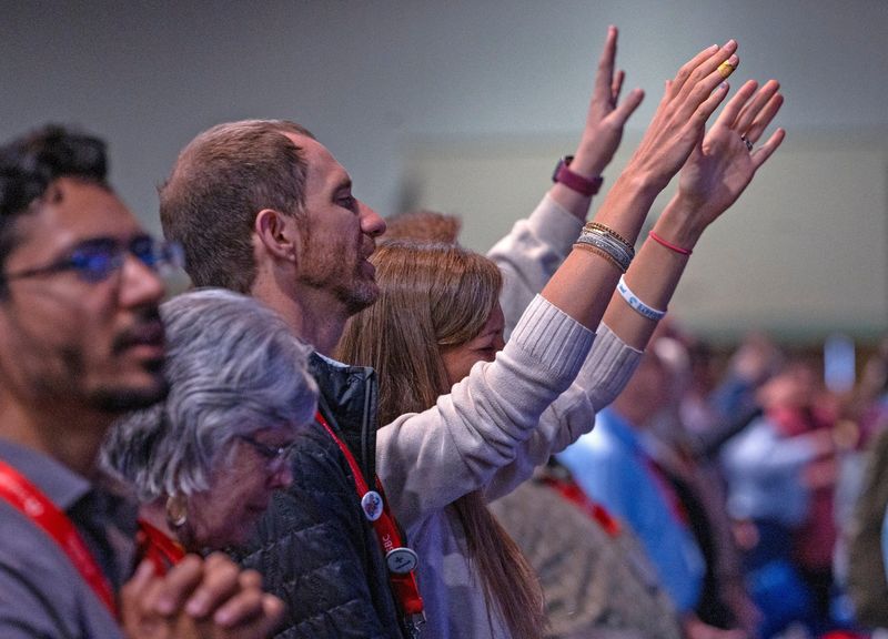 © Reuters. People raise their hands in praise during the Southern Baptist Convention at the Indiana Convention Center in Indianapolis, Indiana, U.S.  June 11, 2024. Kelly Wilkinson/IndyStar/USA Today Network via REUTERS