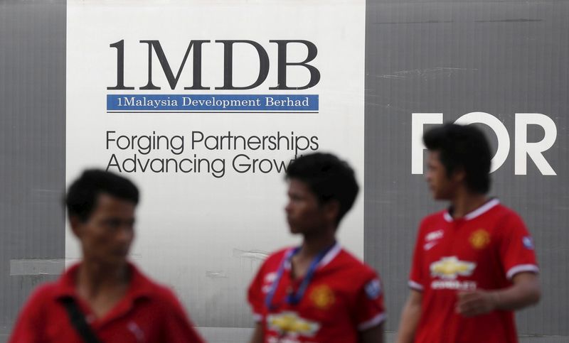 © Reuters. FILE PHOTO: Men walk past a 1Malaysia Development Berhad (1MDB) billboard at the fund's flagship Tun Razak Exchange development in Kuala Lumpur March 1, 2015. REUTERS/Olivia Harris/File Photo