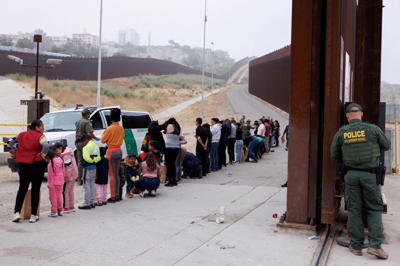 © Reuters. FILE PHOTO: U.S. Border Patrol agents gather and sort migrants who overnight gathered between the primary and secondary border walls that separate Mexico and the United States following the announcement of tough new restrictions imposed by U.S. President Biden in San Diego, California,U.S., June 6, 2024.   REUTERS/Mike Blake/File Photo