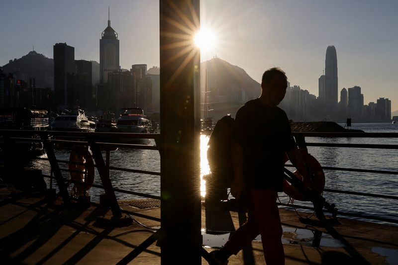 © Reuters.  FILE PHOTO: A man walks along the waterfront with skyline buildings across Victoria Harbor in Hong Kong, China October 24, 2023. REUTERS/Tyrone Siu/File Photo