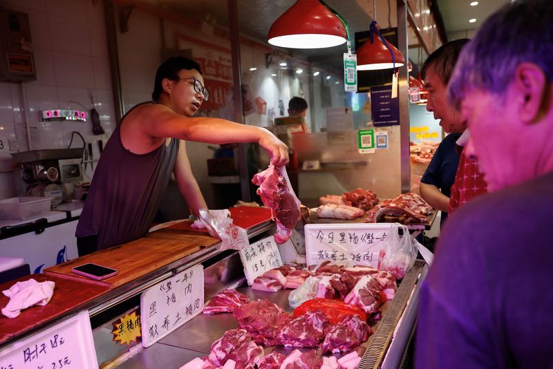 &copy; Reuters. Un venditore di carne di maiale serve un cliente in un mercato a Pechino, Cina, 9 agosto 2023. REUTERS/Tingshu Wang/File Photo