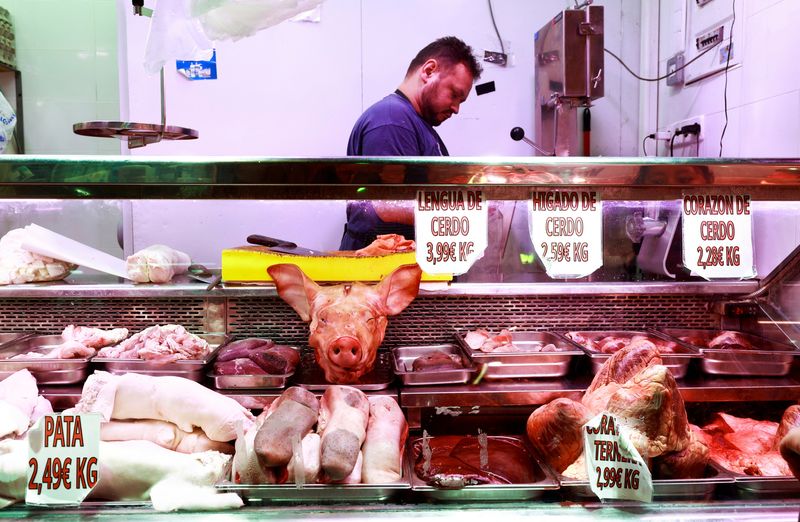 © Reuters. A butcher handles pork pieces at a market stall in Madrid, Spain, June 17, 2024. REUTERS/Juan Medina