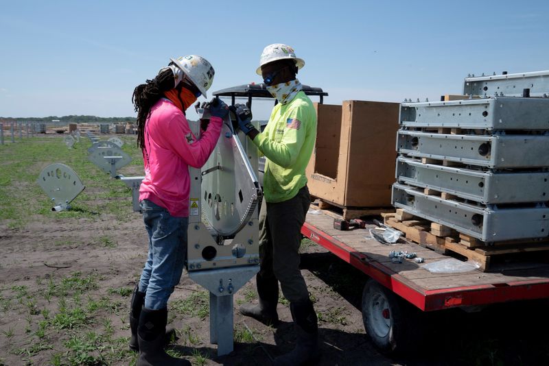 © Reuters. FILE PHOTO: Construction workers Tekovin Miller and Darien Bailey install actuators for tilting panels at the Duette solar site which is being developed on previously agricultural land in Bowling Green, Florida, U.S., March 24, 2021. Picture taken March 24, 2021. REUTERS/Dane Rhys/File Photo
