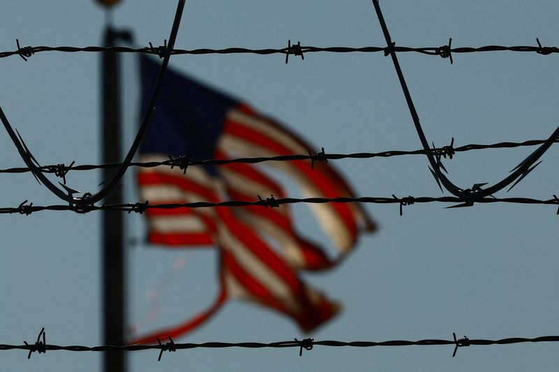 © Reuters. A United States flag is seen near the El Paso airport as Guatemalan migrants, mostly shackled, are being transported to a plane to be expelled from the United States to their country of origin by agents of the U.S. Immigration and Customs Enforcement (ICE) and Border Patrol agents, at the El Paso airport, Texas, U.S., June 13, 2024. REUTERS/Jose Luis Gonzalez/File Photo