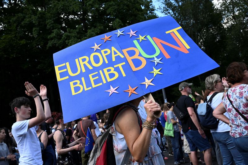 &copy; Reuters. FILE PHOTO: A woman carries a banner with lettering 'Europe stay colorful' during a demonstration against right-wing extremism and for the protection of democracy ahead of the European Parliament elections, near the Victory Column in Berlin, Germany, June