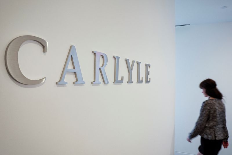 &copy; Reuters. A woman walks next to the logo for Carlyle at the company’s offices in New York City, U.S., June 28, 2022. Picture taken June 28, 2022. REUTERS/Brendan McDermid/ File Photo
