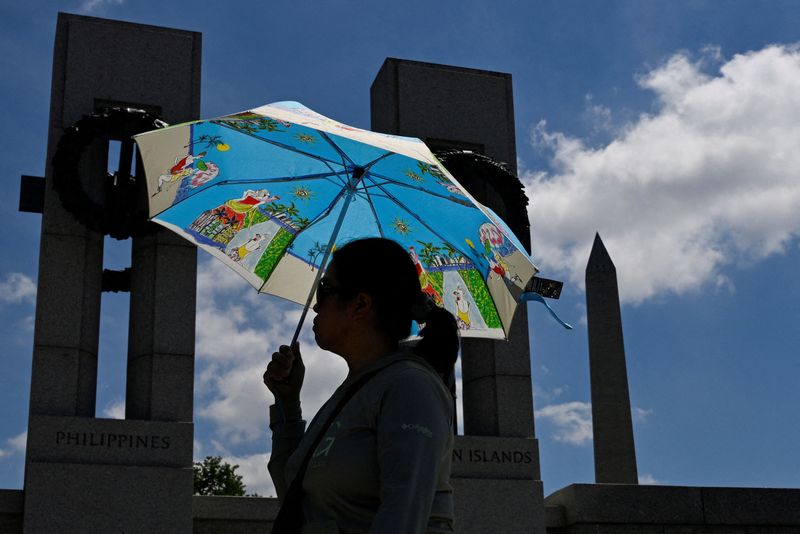 © Reuters. FILE PHOTO: A visitor shields herself from the sun with an umbrella at the World War II Memorial amid a heat wave in Washington, U.S., June 19, 2024. REUTERS/Craig Hudson/File Photo