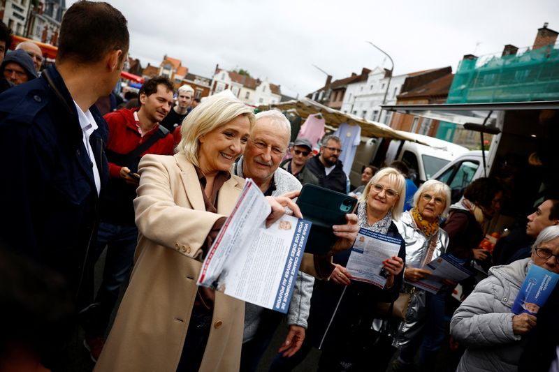 &copy; Reuters. FILE PHOTO: Marine Le Pen, French far-right leader and French far-right National Rally (Rassemblement National - RN) party candidate in the upcoming parliamentary elections, makes a selfie with supporters as she campaigns at a market in Henin-Beaumont, no