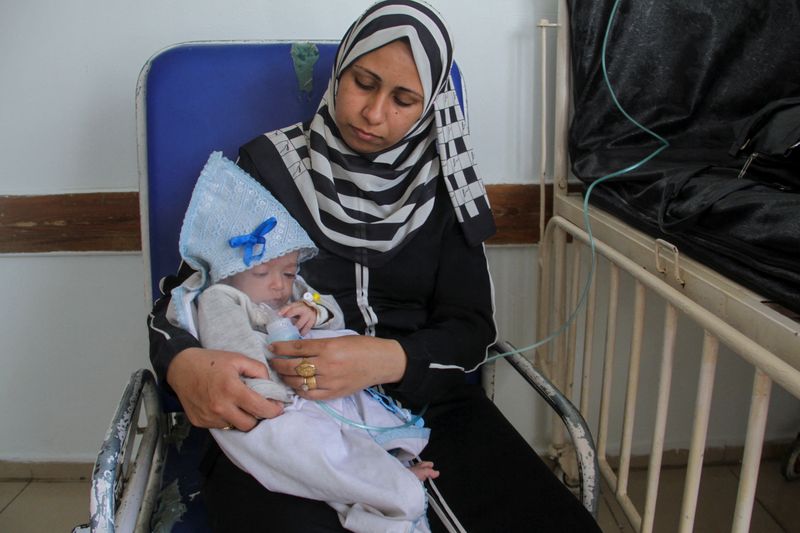 © Reuters. Palestinian woman Nisreen gives nebulizer treatment to her son Majd Salem, a six-month-old malnourished Palestinian baby who weighed 3.5 kg when he was born and gained just 300 grams in six months, at Kamal Adwan hospital in the northern Gaza Strip May 9, 2024. REUTERS/Mahmoud Issa