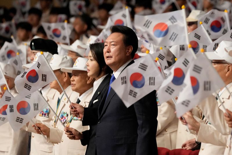 © Reuters. South Korean President Yoon Suk Yeol, center right and his wife Kim Keon Hee wave the national flags during a ceremony to mark the 74th anniversary of the outbreak of the Korean War in Daegu, South Korea, Tuesday, June 25, 2024. Ahn Young-joon/Pool via REUTERS
