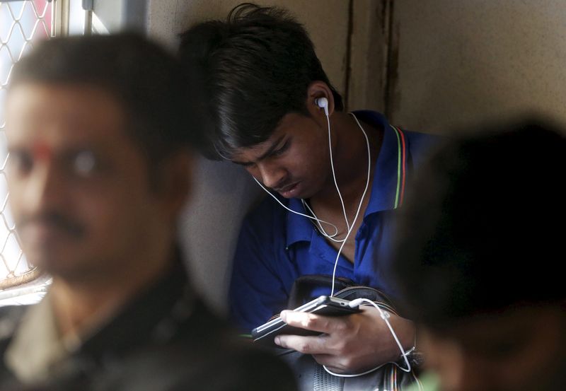 © Reuters. FILE PHOTO: A man watches a video on his mobile phone as he commutes by a suburban train in Mumbai, India, March 31, 2016. REUTERS/Shailesh Andrade/FIle Photo