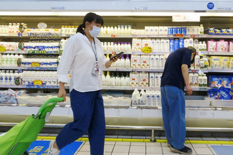 © Reuters. FILE PHOTO: A customer picks milk from refrigerator shelves at a supermarket in Beijing, China, May 21, 2021. REUTERS/Thomas Peter/File Photo