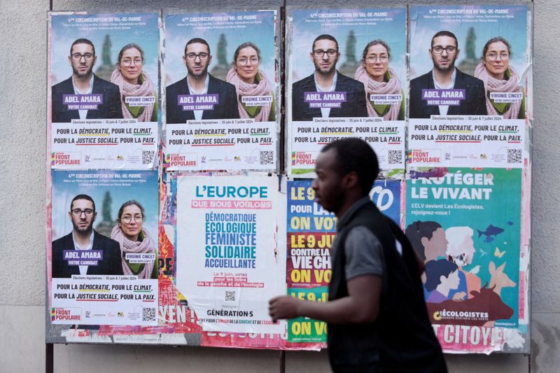 © Reuters. FILE PHOTO: A man walks past campaign posters for Adel Amara, candidate for the French left wing alliance, named the New Popular Front (Nouveau Front Populaire - NFP), for the upcoming French parliamentary elections, in Le Plessis-Trevise near Paris, France, June 19, 2024. REUTERS/Abdul Saboor/File Photo