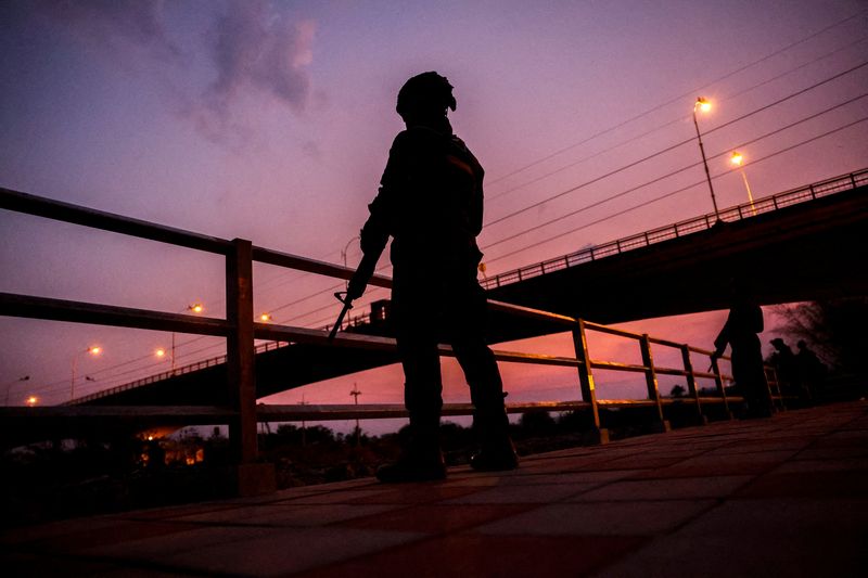 &copy; Reuters. FILE PHOTO: Military personnel stand guard as hundreds of refugees crossed over the river frontier between Myanmar and Thailand on Friday, following the fall of a strategic border town to rebels fighting Myanmar's military junta, in Mae Sot, Tak province,