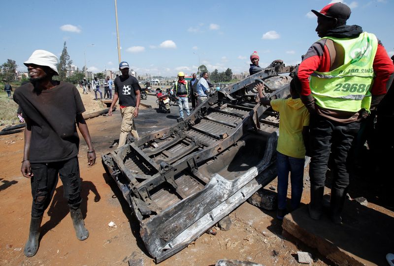 ©Reuters.  People stand next to a police car that was burned during demonstrations against Kenya's proposed 2024/2025 finance bill in Nairobi, Kenya, June 26, 2024.