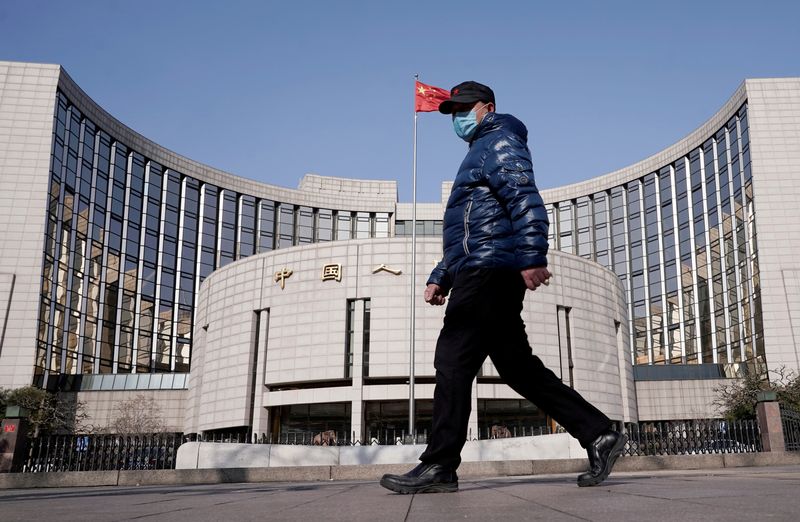 © Reuters. FILE PHOTO: A man wearing a mask walks past the headquarters of the People's Bank of China, the central bank, in Beijing, China, as the country is hit by an outbreak of the new coronavirus, February 3, 2020. REUTERS/Jason Lee/File Photo
