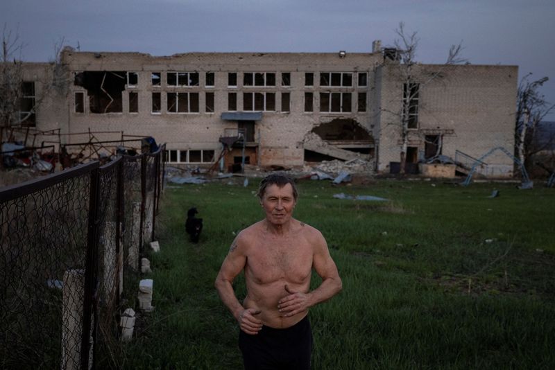 © Reuters. FILE PHOTO: Yurii, a villager, runs laps in the sports ground of the school where he worked which was destroyed during heavy fighting between Russian and Ukrainian forces in the village of Dolyna in the Donetsk region, amid Russia's attack on Ukraine, April 11, 2024.  REUTERS/Thomas Peter/File Photo