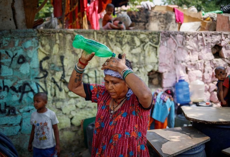 &copy; Reuters. FILE PHOTO: A woman pours water on her head after filling her containers with drinking water from a municipal tanker on a hot summer day in New Delhi, India, May 21, 2024. REUTERS/Adnan Abidi/File Photo