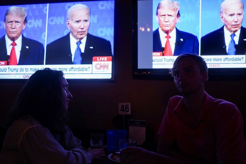 © Reuters. Republican presidential candidate, former U.S. President Donald Trump and Democrat presidential candidate, U.S. President Joe Biden are seen on television as people attend a watch party for the first U.S. presidential debate hosted by CNN in Atlanta, at Union Pub on Capitol Hill in Washington, U.S., June 27, 2024. REUTERS/Nathan Howard