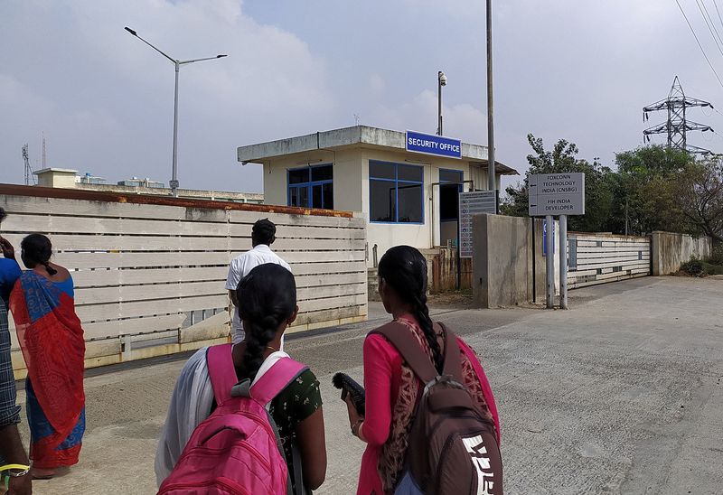© Reuters. FILE PHOTO: Two unidentified women wearing backpacks stand outside a security office at the main entrance to Foxconn's factory in Sriperumbudur, near Chennai, where workers assemble iPhones for Apple, January 28, 2023. REUTERS/Praveen Paramasivam/File Photo