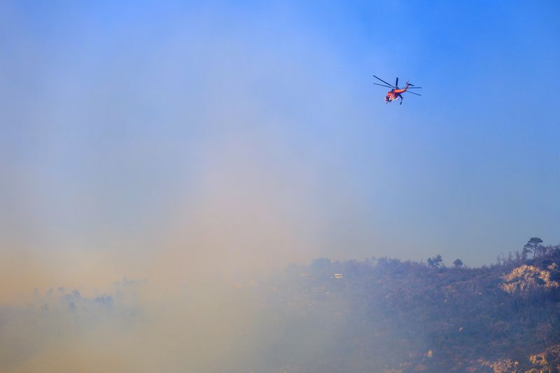 &copy; Reuters. A firefighting helicopter operates, as a wildfire burns on Mount Parnitha, near Athens, Greece, June 29, 2024. REUTERS/Elias Marcou