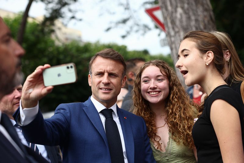 © Reuters. Emmanuel Macron takes a selfie with supporters, Le Touquet-Paris-Plage, June 30, 2024. REUTERS/Yara Nardi
