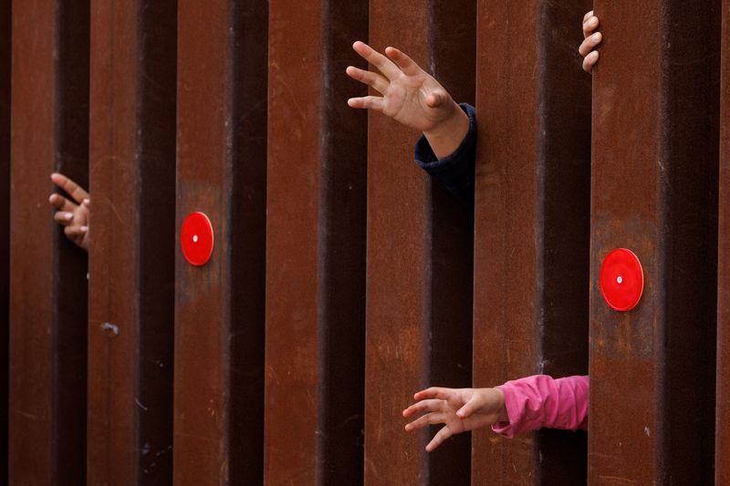 © Reuters. FILE PHOTO: A child's hand reaches out, as migrants wait for food and water to be handed handed out, after gathering between the primary and secondary border fences, between the United States and Mexico, after the lifting of COVID-19 era Title 42 restrictions that have blocked migrants at the border from seeking asylum since 2020, near San Diego, California, U.S., May 12, 2023. REUTERS/Mike Blake/File Photo
