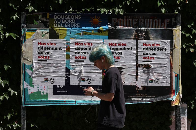 &copy; Reuters. FILE PHOTO: A person walks past posters which read "our lives depend on your votes", during the first round of the early French parliamentary elections, in Nantes, France, June 30, 2024. REUTERS/Violeta Santos Moura/File Photo