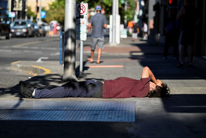 © Reuters. FILE PHOTO: A man lies on a sidewalk during a heatwave in Portland, Oregon, U.S., August 11, 2021.  REUTERS/Mathieu Lewis-Rolland/File Photo