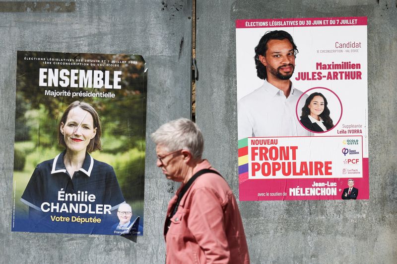 © Reuters. A person walks past election campaign posters prior to the second round of the early French parliamentary elections, in Magny-en-Vexin, France, July 4, 2024. REUTERS/Yara Nardi