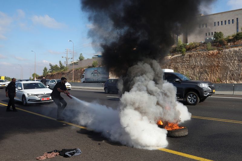 &copy; Reuters. A person works to extinguish a fire lit by anti-government protestors on a day of protests marking 9 months since the deadly October 7 attack, under the slogan "Israel comes to a standstill", near Shoresh, Israel, July 7, 2024. REUTERS/Ronen Zvulun