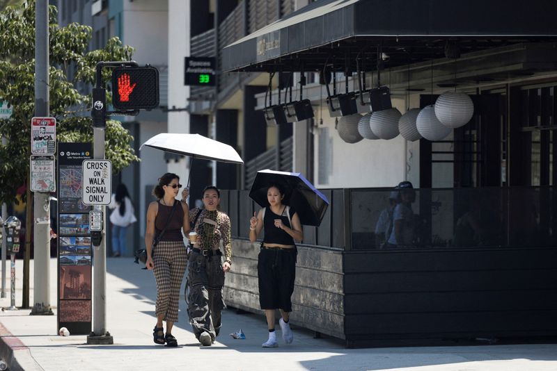 © Reuters. FILE PHOTO: People hold an umbrella to protect themselves from the sun in Little Tokyo during hot weather in Los Angeles, California, U.S. July 5, 2024.  REUTERS/Etienne Laurent/File Photo