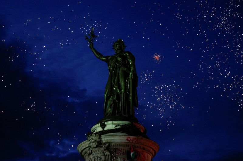 © Reuters. Tượng Marianne được nhìn thấy giữa màn pháo hoa khi mọi người tụ tập tại Place de la Republique sau kết quả một phần trong vòng hai của cuộc bầu cử quốc hội Pháp sớm, tại Paris, Pháp, ngày 7 tháng 7 năm 2024. REUTERS/Abdul Saboor