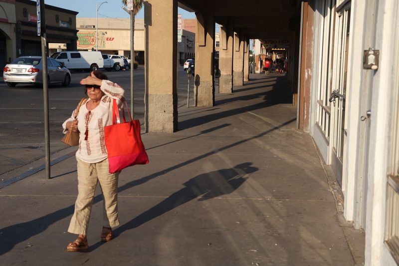 © Reuters. A woman walks through downtown during a period of excessive heat in Calexico, California, U.S. July 7, 2024.  REUTERS/Zoe Meyers