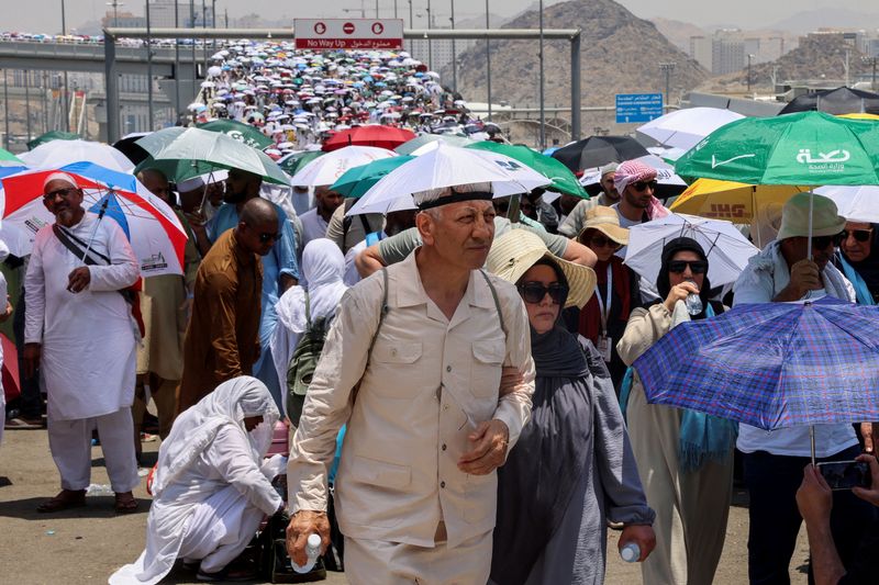 &copy; Reuters. Peregrinos muçulmanos caminham com guarda-chuvas no terceiro dia do ritual de apedrejamento de Satanás, em meio a um clima extremamente quente, durante peregrinação anual do hajj, em Mina, Arábia Sauditan18/07/2024nREUTERS/Saleh Salem