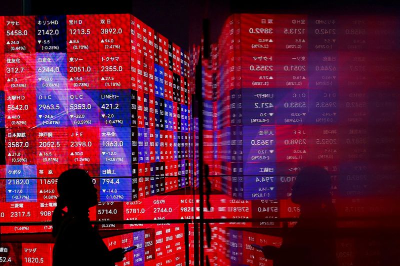 © Reuters. FILE PHOTO: A visitor stands next to an electronic screen displaying Japan's Nikkei stock prices quotation board as the average surged past an all-time record high scaled in December 1989, inside a building in Tokyo, Japan February 22, 2024.  REUTERS/Issei Kato/File Photo