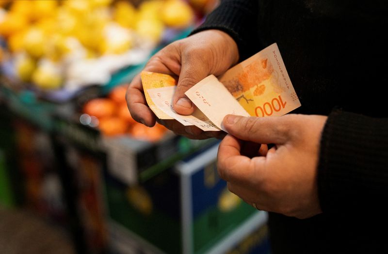 &copy; Reuters. A greengrocer counts Argentine peso bills at a local market,as Argentina is due to release consumer inflation data for April, in Buenos Aires, Argentina May 11, 2024. REUTERS/Irina Dambrauskas/File photo