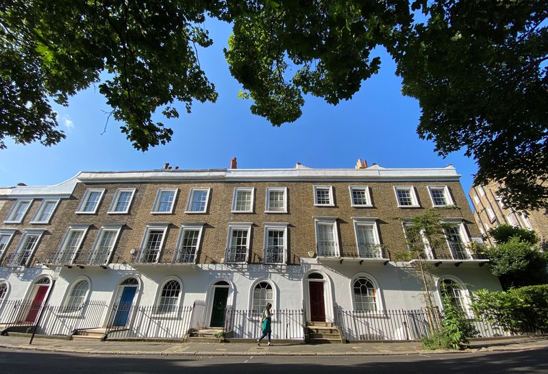 © Reuters. FILE PHOTO: A woman walks past houses on a leafy street early in the morning in Islington, London, Britain, June 22, 2020.   REUTERS/Simon Newman/File Photo