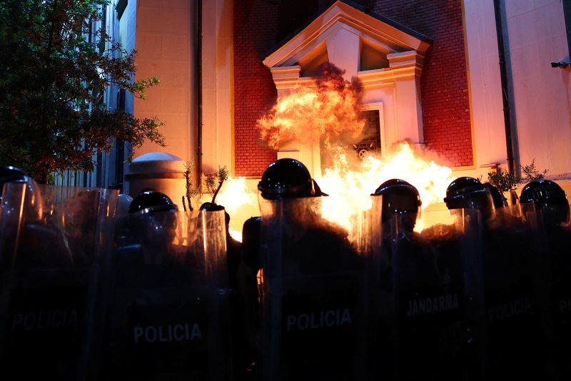 © Reuters. Police officers react to the fire after a Molotov cocktail was thrown, while supporters of the opposition attend an anti-government protest, in front of Tirana’s Mayors office, in Tirana, Albania, July 11, 2024. REUTERS/Florion Goga