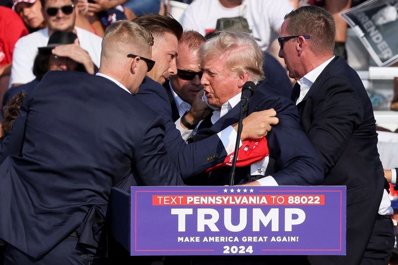 © Reuters. Republican presidential candidate and former U.S. President Donald Trump is assisted by guards during a campaign rally at the Butler Farm Show in Butler, Pennsylvania, U.S., July 13, 2024. REUTERS/Brendan McDermid     TPX IMAGES OF THE DAY