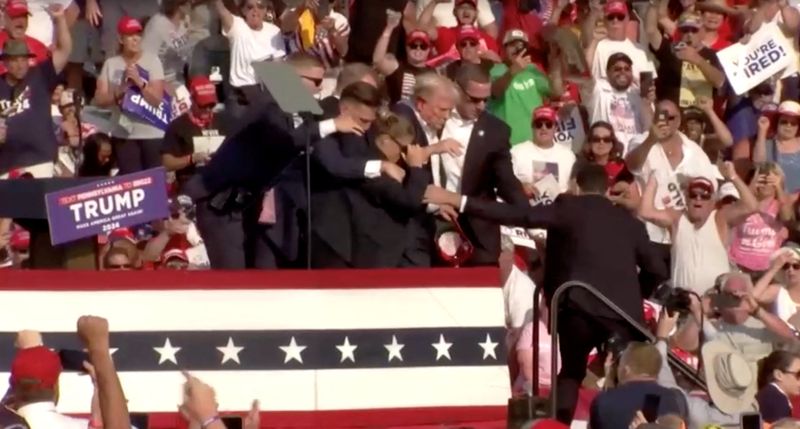 &copy; Reuters. Security escort Republican presidential candidate and former U.S. President Donald Trump away from rally after gunfire rings out during a campaign rally at the Butler Farm Show in Butler, Pennsylvania, U.S., July 13, 2024, in this screen grab taken from a