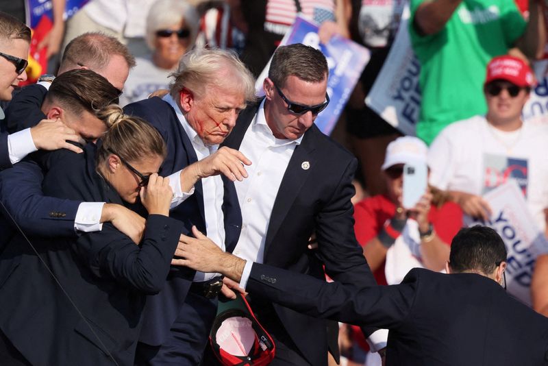 &copy; Reuters. Republican presidential candidate and former U.S. President Donald Trump with his bloodied face is assisted by the Secret Service as multiple shots rang out during a campaign rally at the Butler Farm Show in Butler, Pennsylvania, U.S., July 13, 2024. REUT