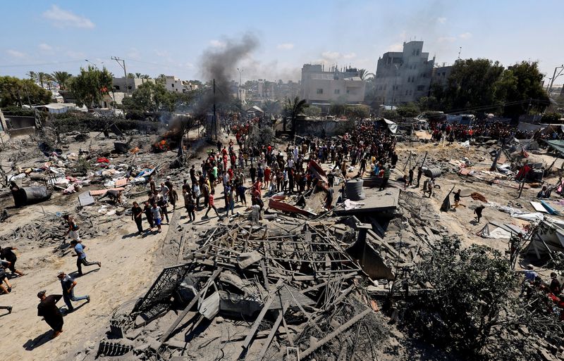 © Reuters. FILE PHOTO: Palestinians gather near damage, following what Palestinians say was an Israeli strike at a tent camp in Al-Mawasi area, amid Israel-Hamas conflict, in Khan Younis in the southern Gaza Strip July 13, 2024. REUTERS/Mohammed Salem/File Photo