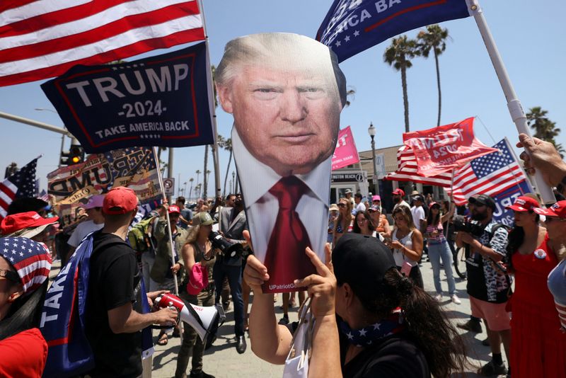 © Reuters. A pro-Trump supporter holds a portrait of former President Donald Trump during a demonstration in support of former U.S. President Donald Trump who was shot the previous day in an assassination attempt during a rally in Pennsylvania, in Huntington Beach, California, U.S. July 14, 2024.  REUTERS/Etienne Laurent