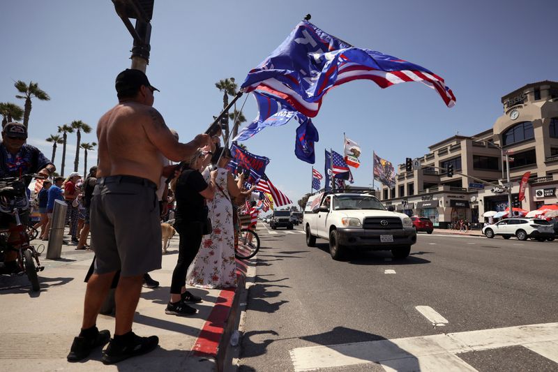 © Reuters. Pro-Trump supporters cheer as a car drives with American and pro-Trump flags during a demonstration in support of former U.S. President Donald Trump who was shot the previous day in an assassination attempt during a rally in Pennsylvania, in Huntington Beach, California, U.S. July 14, 2024.  REUTERS/Etienne Laurent